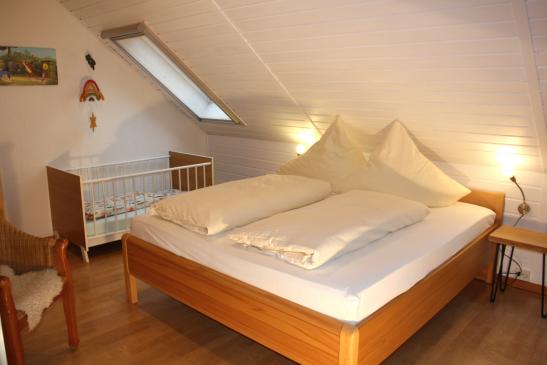 Schlafzimmer OG mit Doppelbett und Holzgitterbettchen