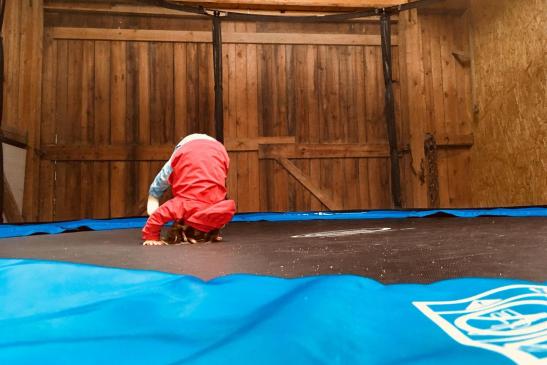 großes Trampolin mit Sicherheitsnetz in der Halle - Sitzgelegenheit für die Großen auch vorhanden